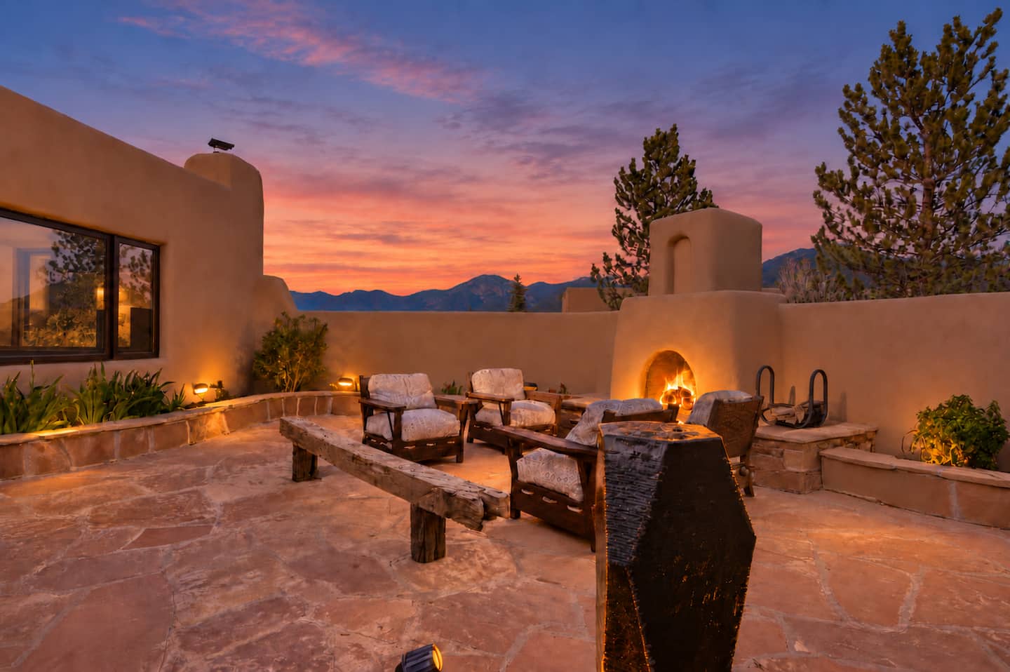 Casa Verdigris courtyard at sunset, with adobe walls and an outdoor kiva fireplace